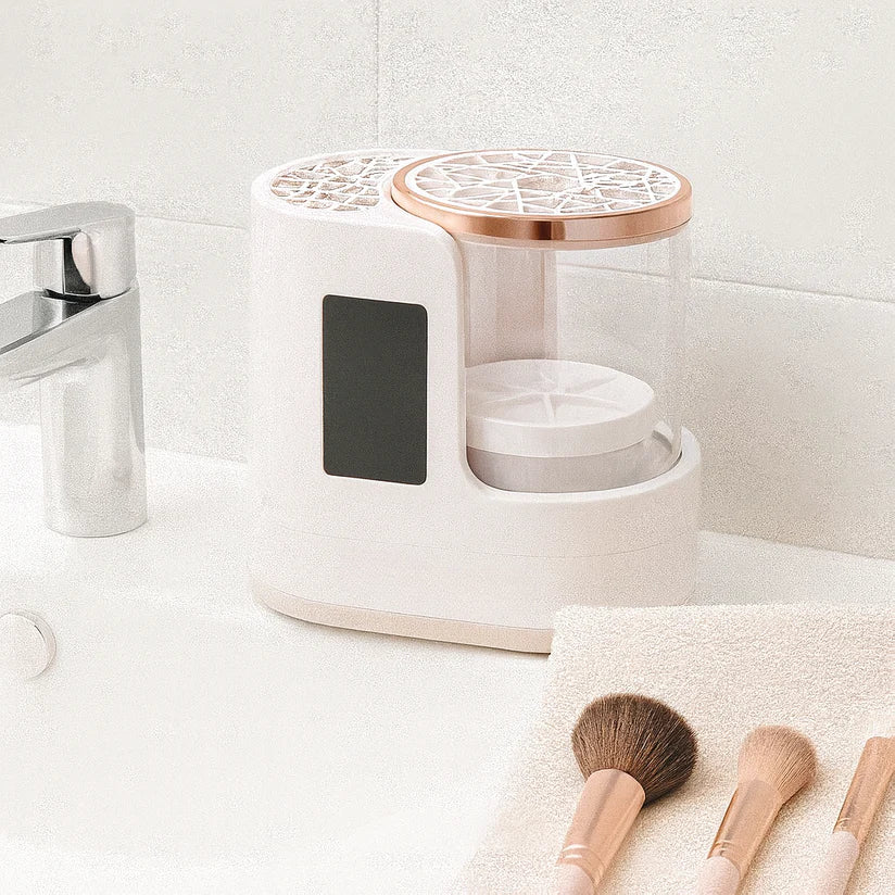 White and rose gold makeup brush holder on a bathroom counter with brushes on a towel.